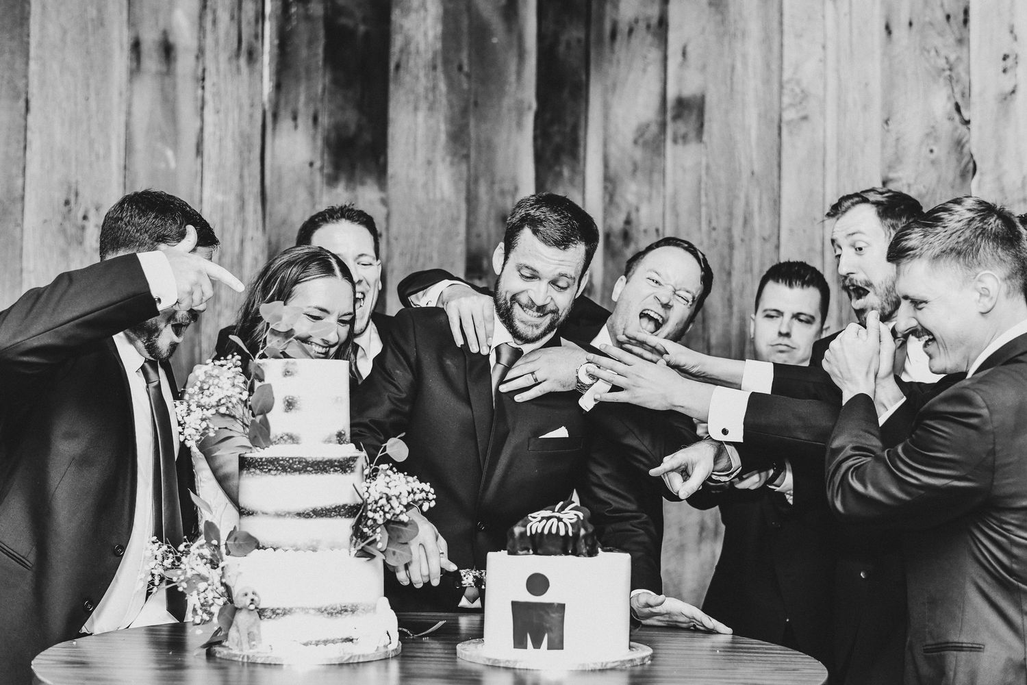 the groom cuts his darth vader groom's cake surrounded by his groomsmen and wife for their wedding cake cutting