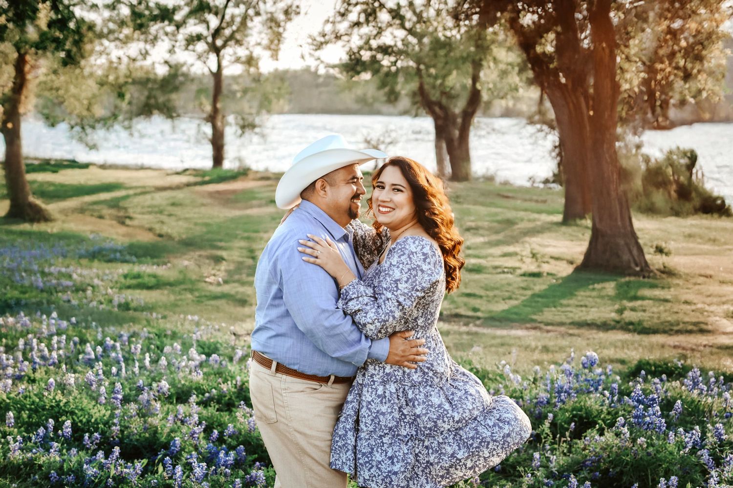 Groom-to-be kissing fiancée’s forehead in a quiet patch of wildflowers along the lakeside at Ennis