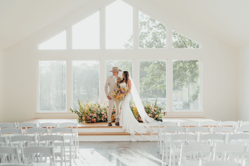 A bright white wedding chapel interior with clear geometric windows and rows of chairs for a ceremony celebration.