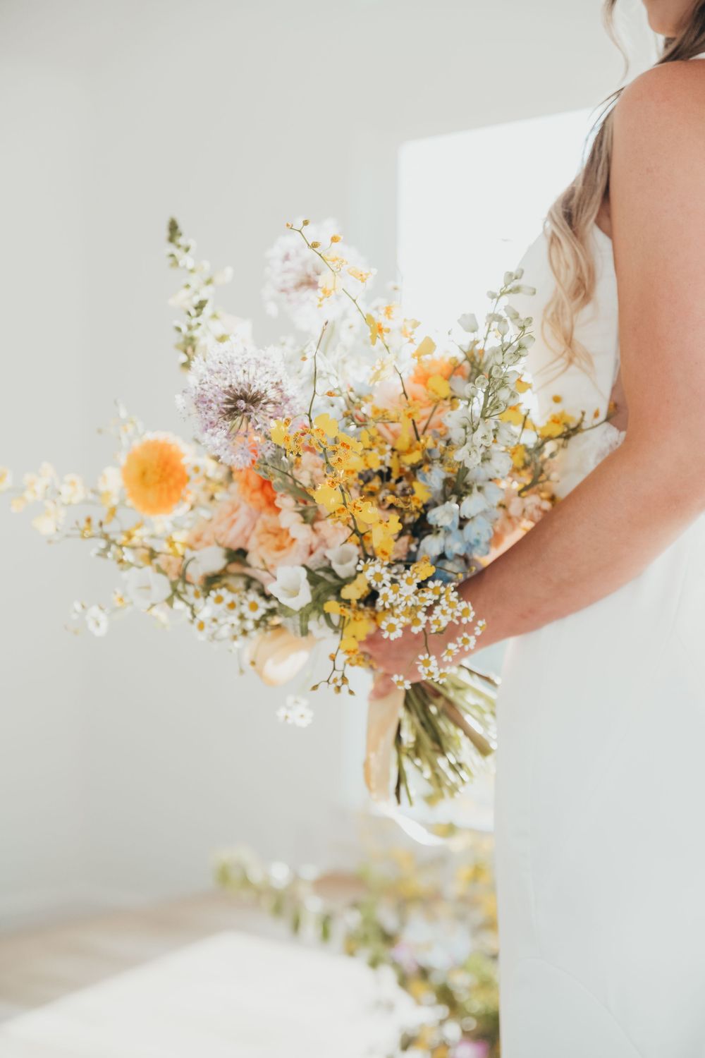 A delicate wildflower wedding bouquet featuring peach, yellow and white blooms with wispy stems.