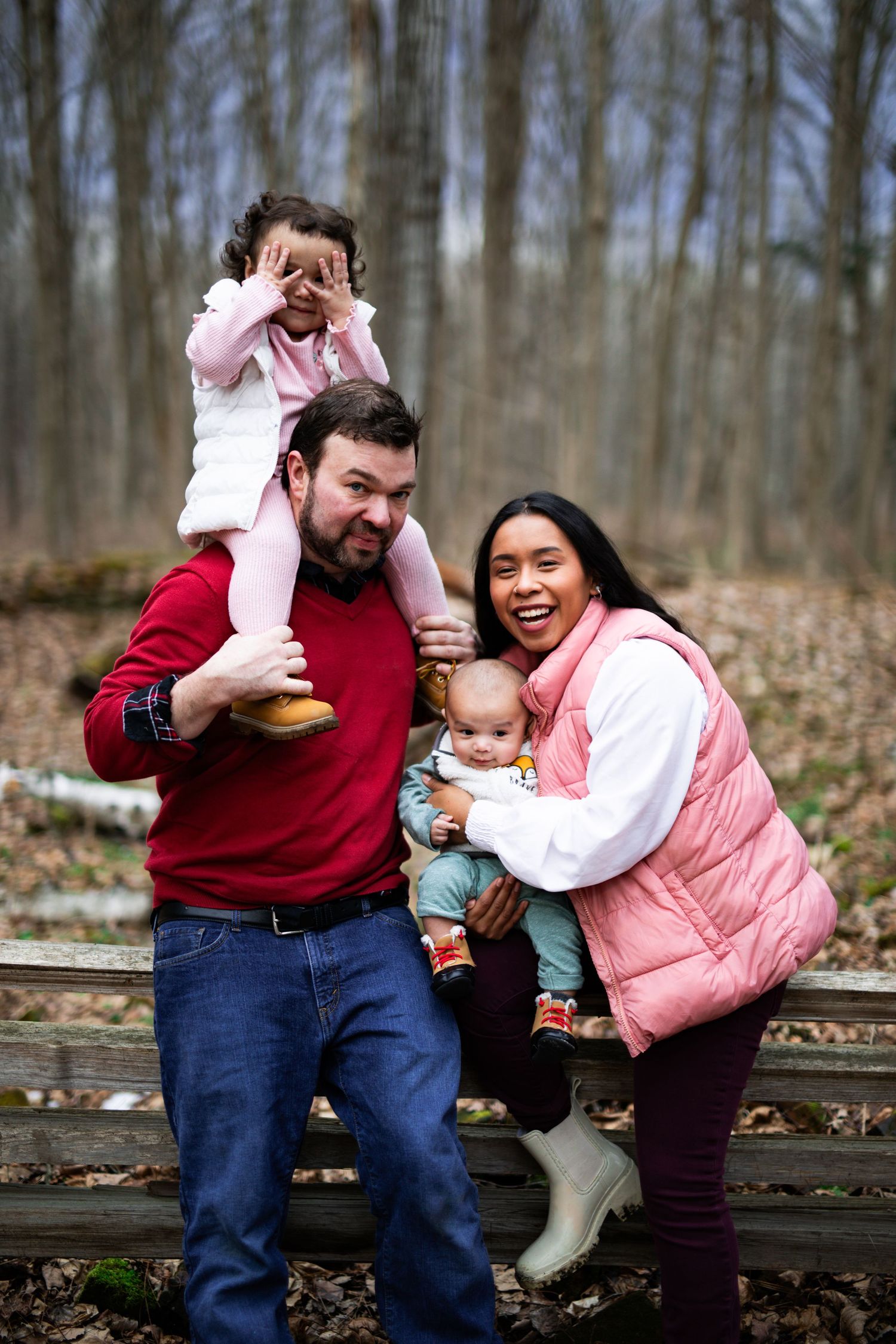 A happy family plays together and shares joyful moments on outdoor steps surrounded by a winter forest.