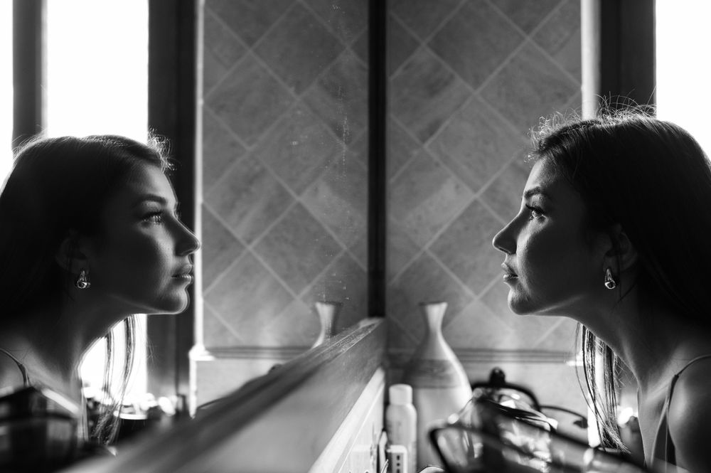 Dramatic black and white reflection of a bride in an elegant mirror.