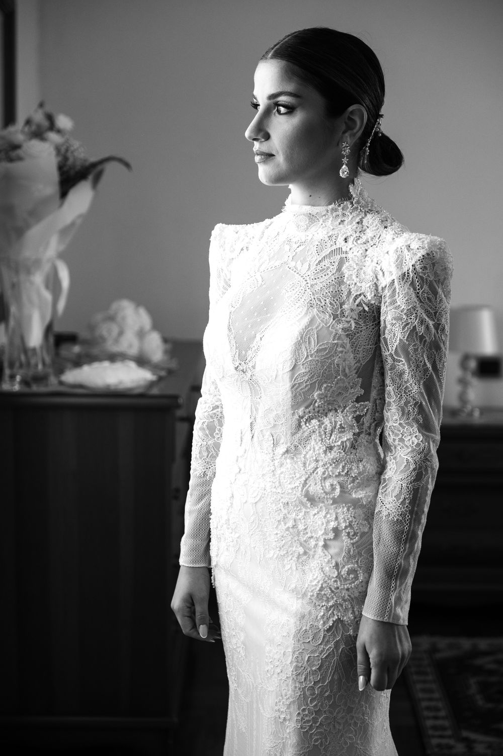 Elegant long-sleeved lace wedding dress shown in striking black and white photography.