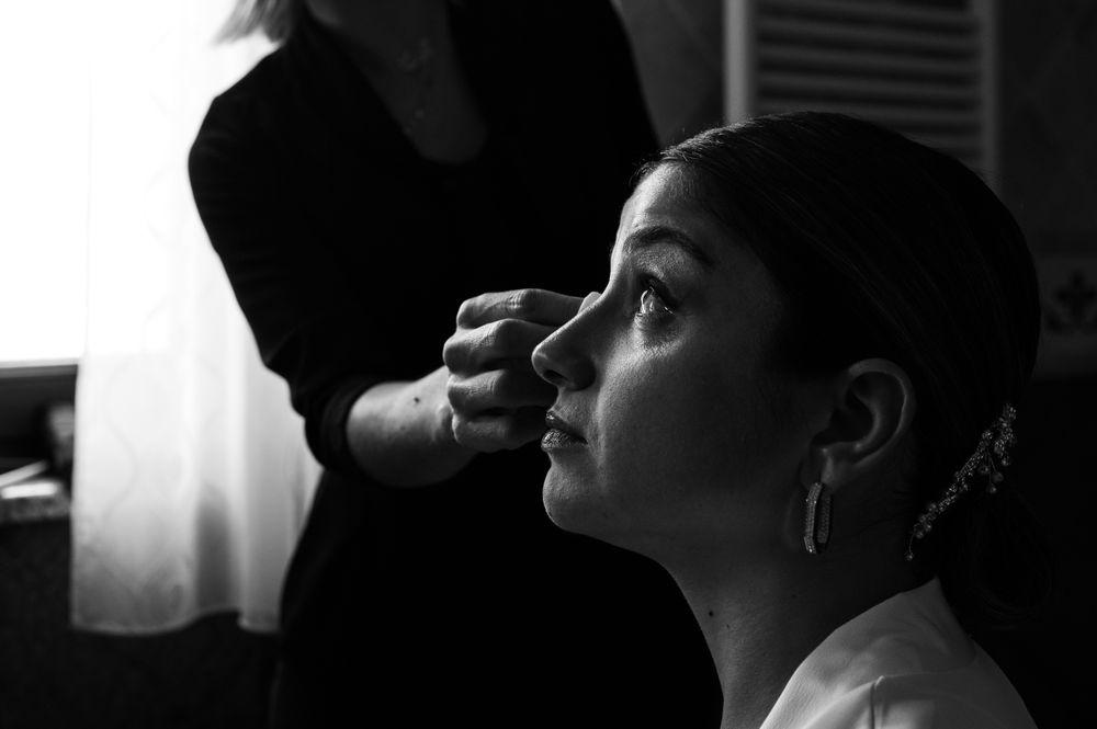 Black and white image of someone getting makeup applied in preparation for a special event.