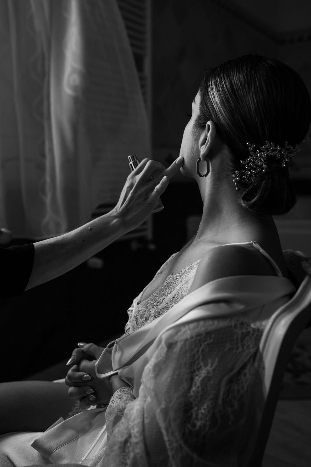 Artistic black and white photo capturing a tender moment during bridal preparation.