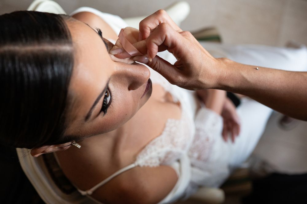 Close-up shot of final makeup touches being applied before a wedding ceremony.