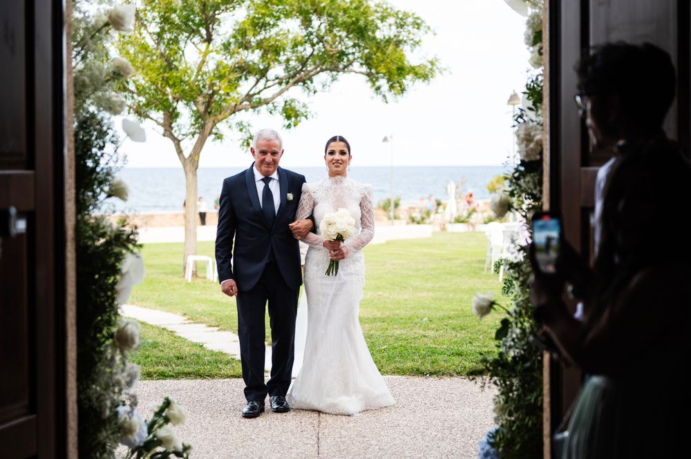 Wedding ceremony entrance framing bride and escort walking through church doors.
