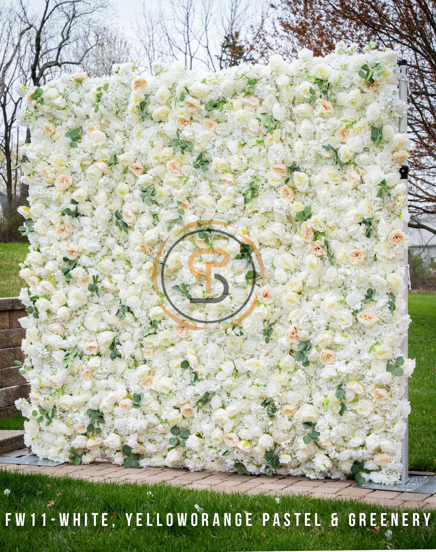 Elegant white floral wall with yellow-orange pastel accents and greenery featuring centered logo.