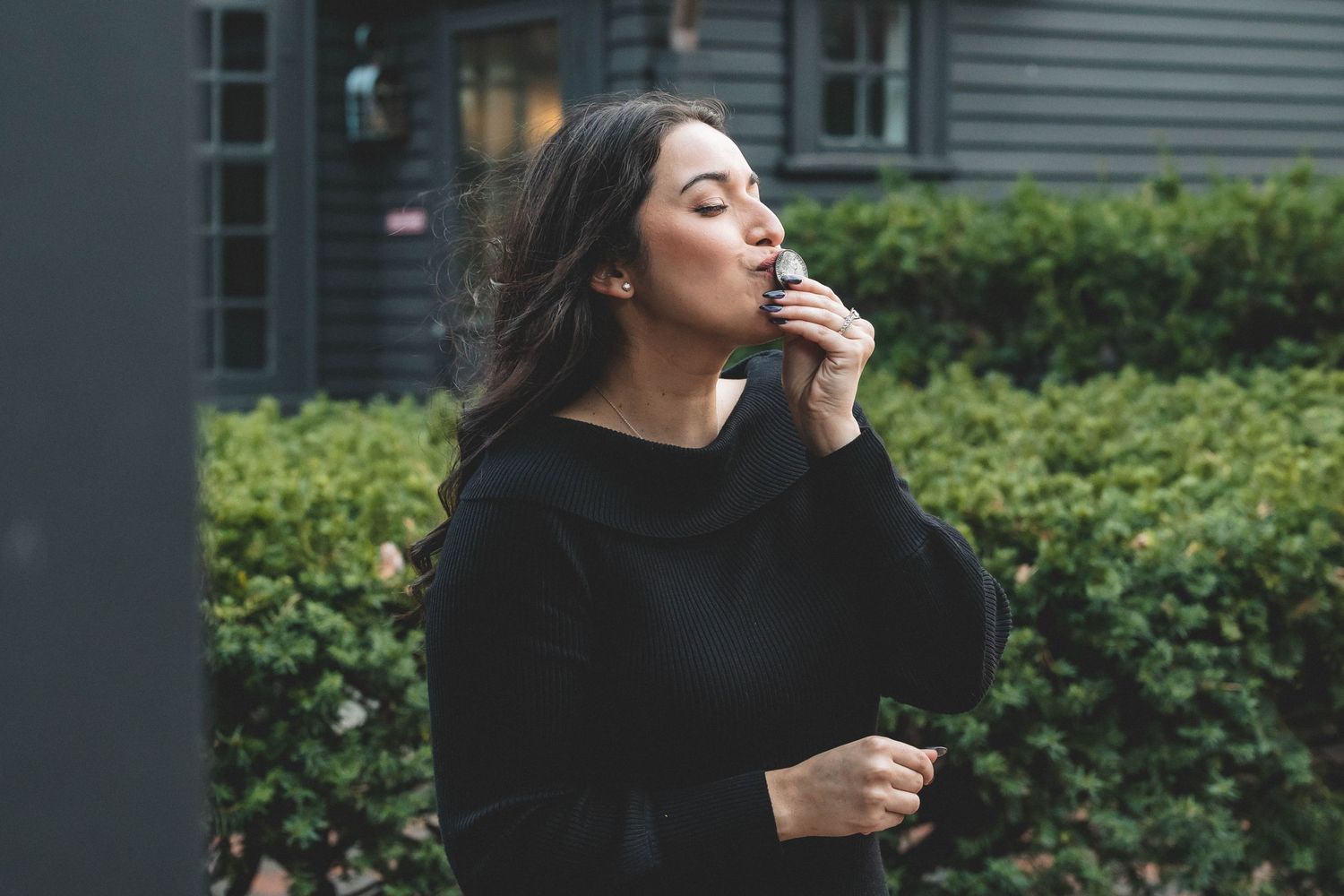 Person in black sweater shows emotional expression outdoors.