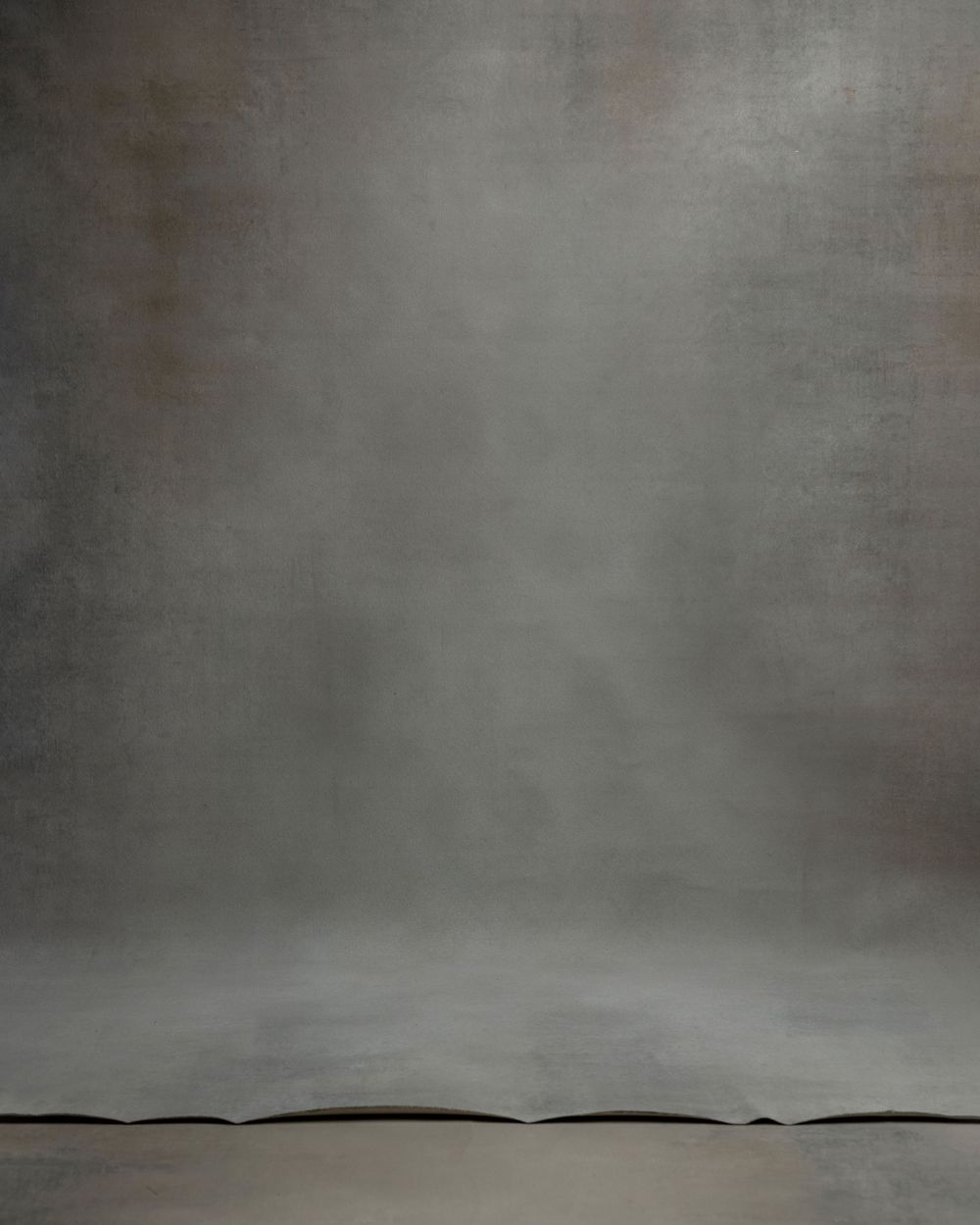 Moody gray studio backdrop with shadowy gradient and rippled bottom edge.