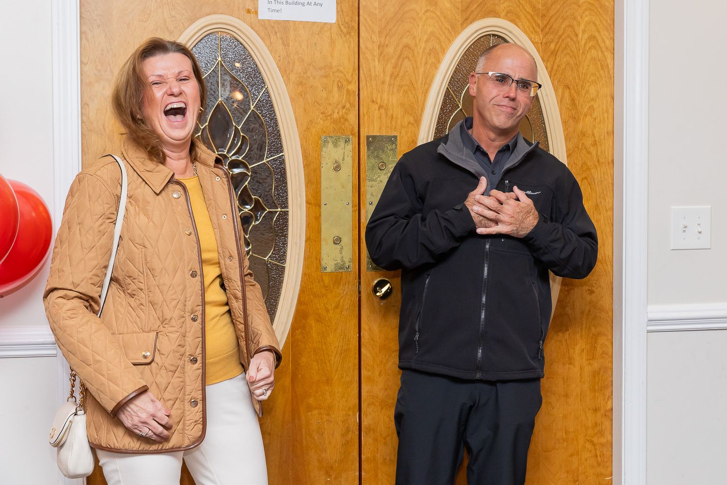 Two people sharing a laugh by a decorated doorway during a celebration.