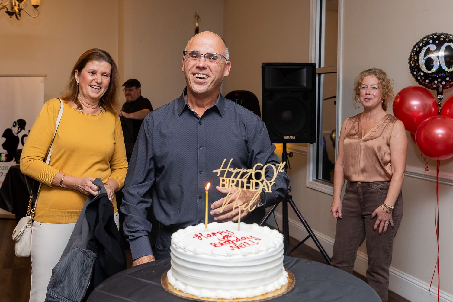 Birthday celebration scene with a cake and red balloons in an indoor setting.