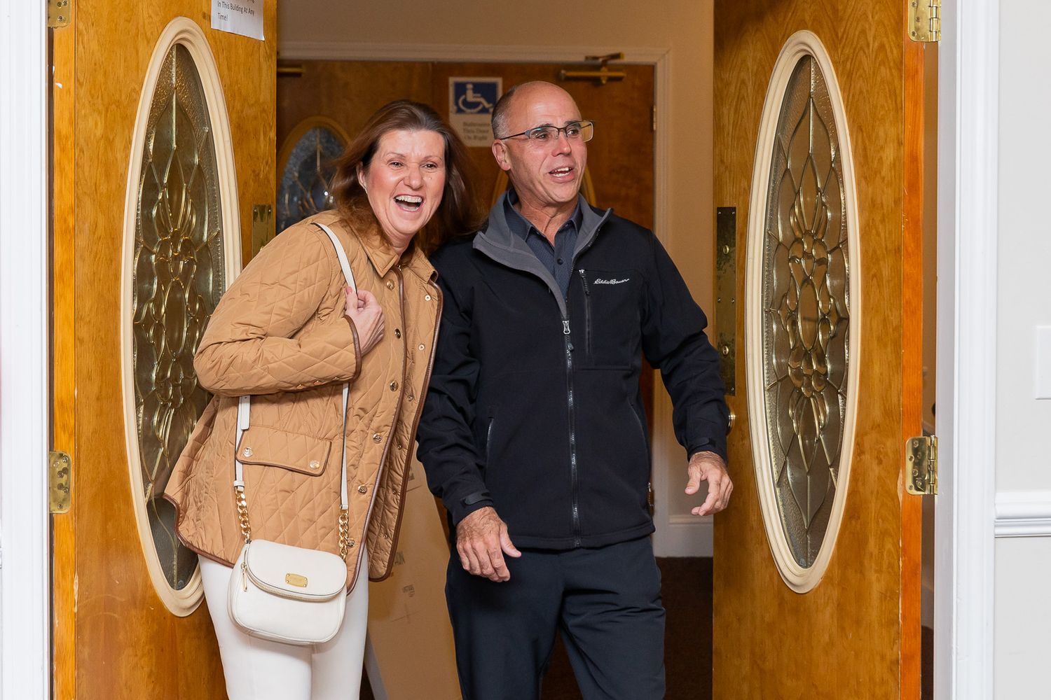 A candid shot of two people walking through a doorway with oval glass panels.