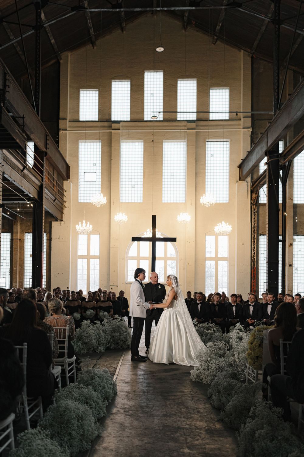 Wedding ceremony in a converted industrial space with high windows and cross altar.