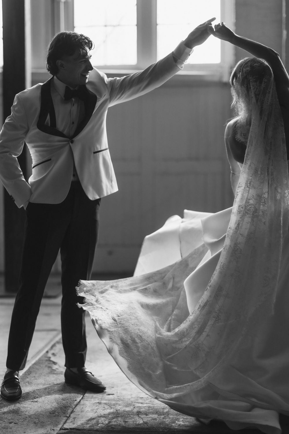 Artistic black and white photo of couple dancing in formal wedding attire.