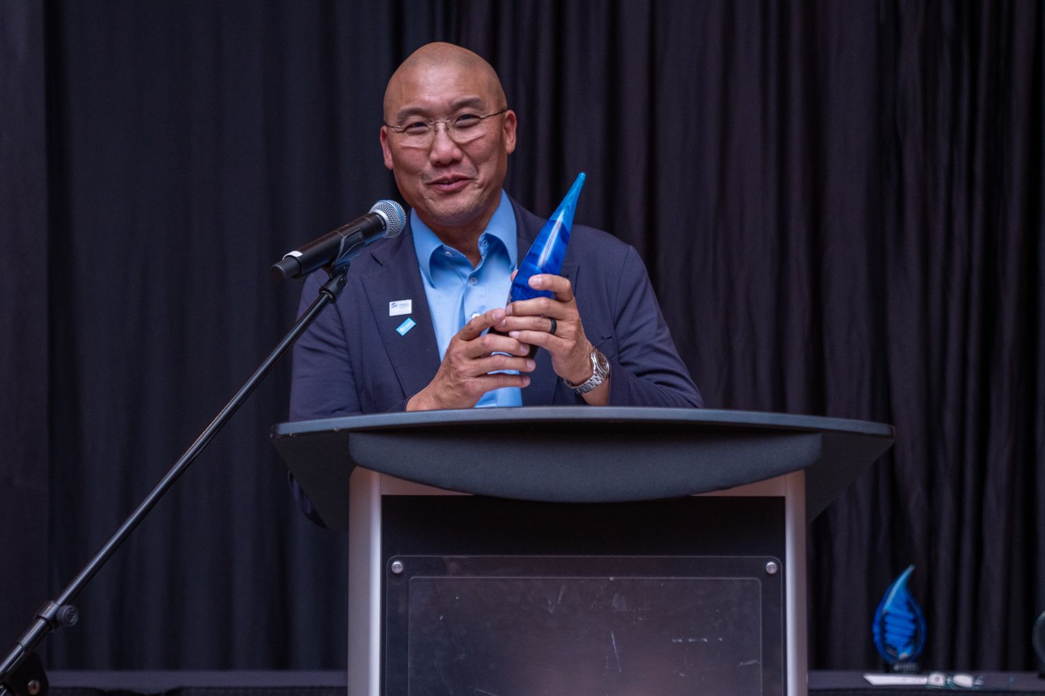 Award recipient at a podium during a professional conference event.