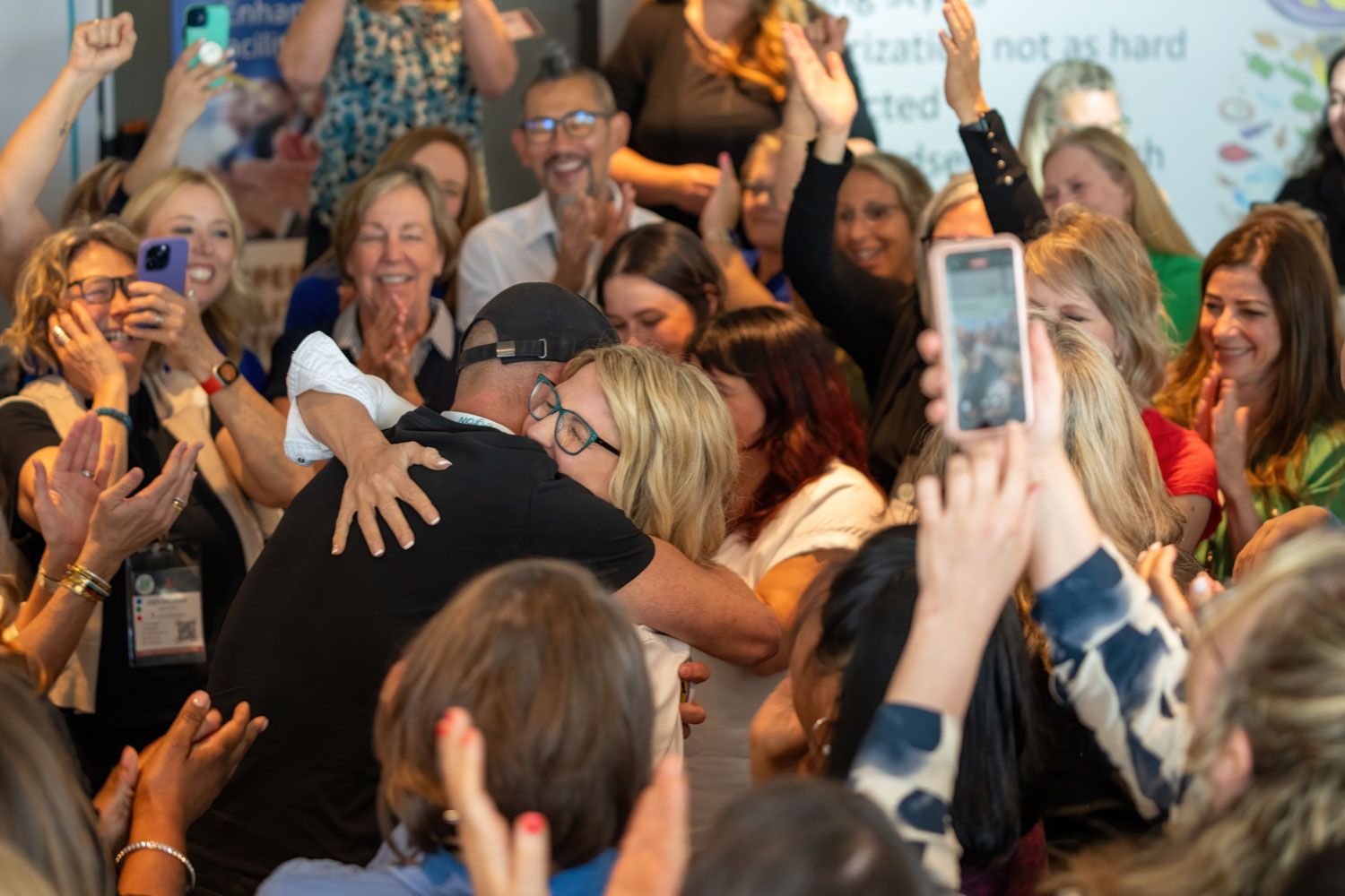 Crowd of excited attendees at an event holding up phones to capture a moment.