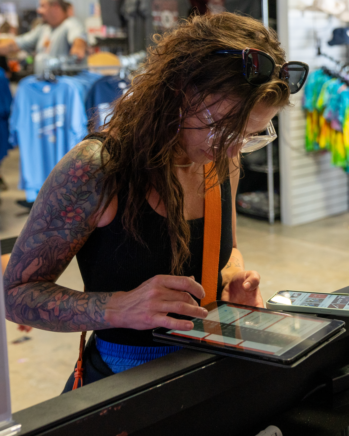 Woman with tattoos using digital tablet at checkout counter.