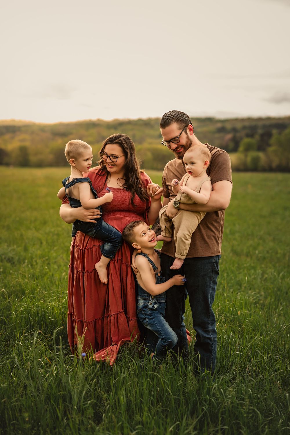 Family shares playful moments together in a green grassy meadow during golden hour.
