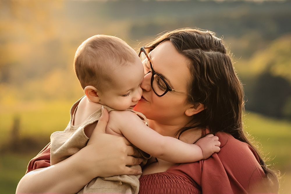 A tender moment between a mother and child outdoors during golden hour in nature.