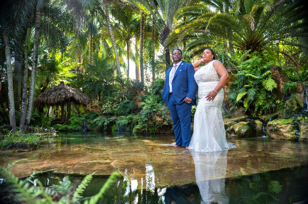 Bride and groom seated on stone bench under canopy of trees, taken by wedding photographers in South Florida.