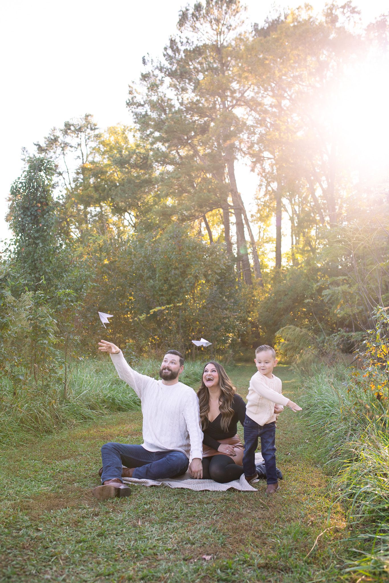 Sunlit family photo shoot at Sugg Farm with paper airplane being thrown during golden hour.