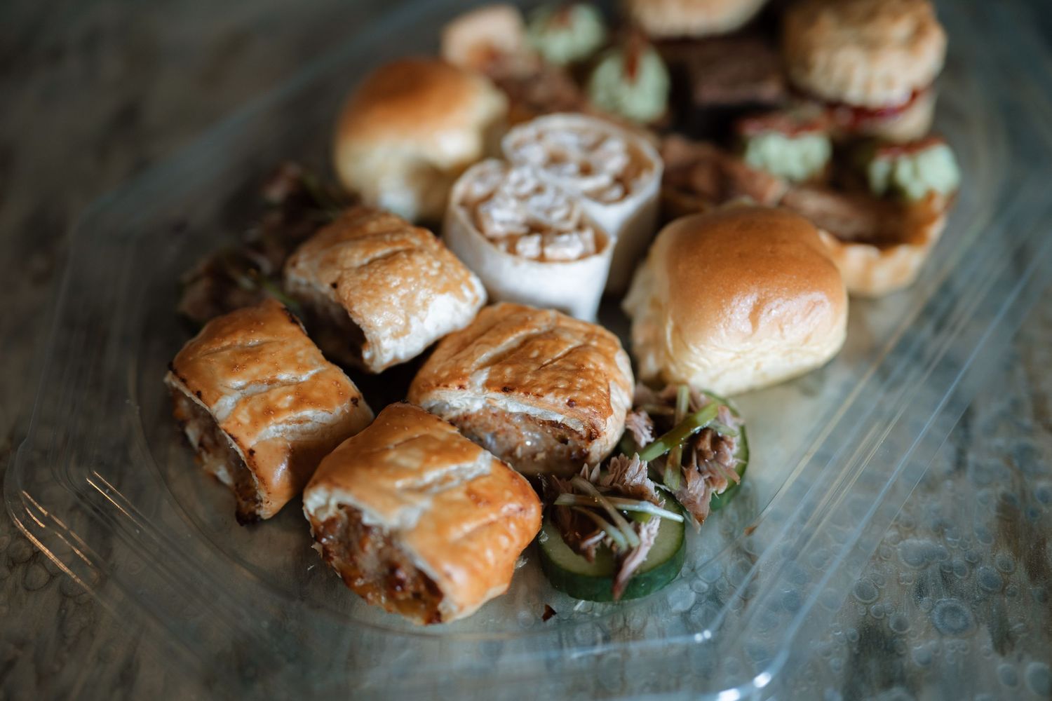 Plate of gourmet sliders or mini sandwiches with various fillings on a rustic wooden surface.