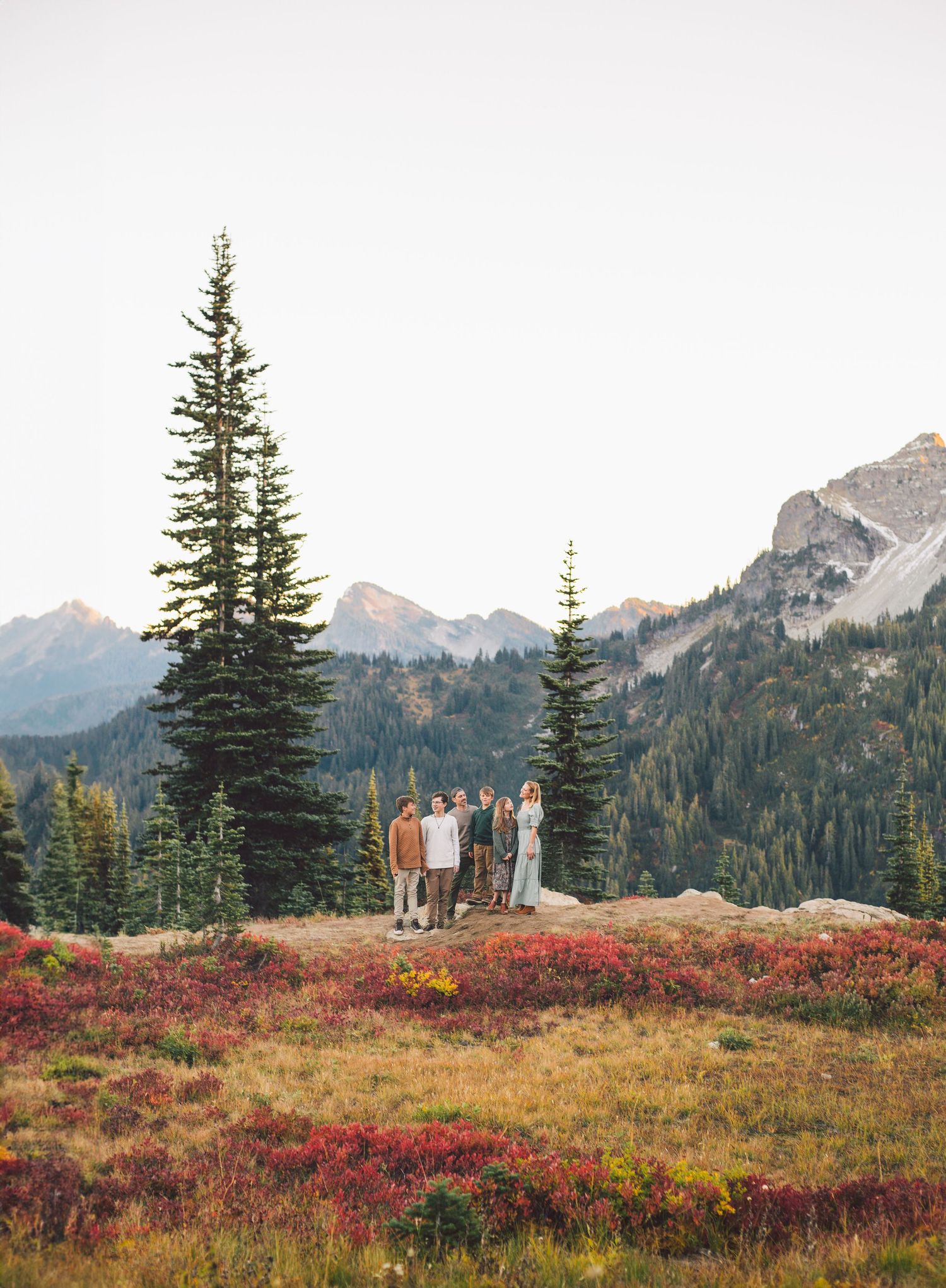 Family standing together in Fall Foliage and a scenic ridge-line during family photoshoot at Mt. Rainier National Park in Washington
