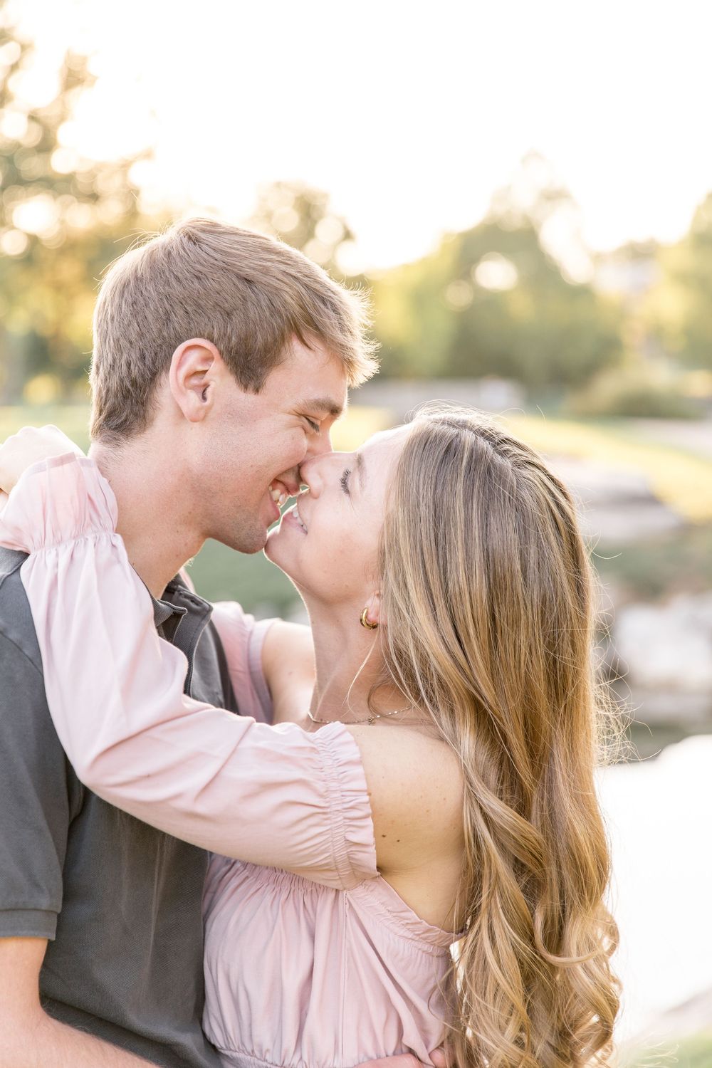 Romantic couple embracing and laughing together outdoors during golden hour at sunset.