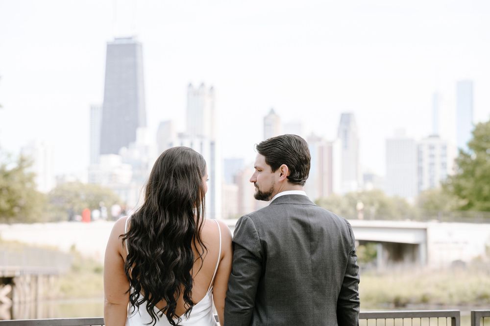 Two people in formal attire look out at the Chicago skyline from an elevated viewpoint.