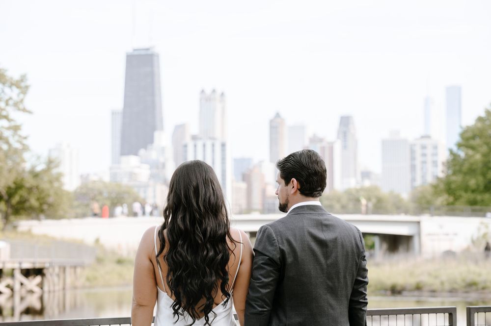 A couple standing together overlooking the Chicago skyline from a bridge on a sunny autumn day.