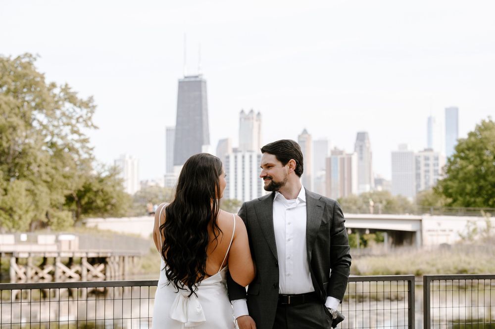 A couple shares a romantic moment on a bridge overlooking the Chicago skyline on an autumn day.