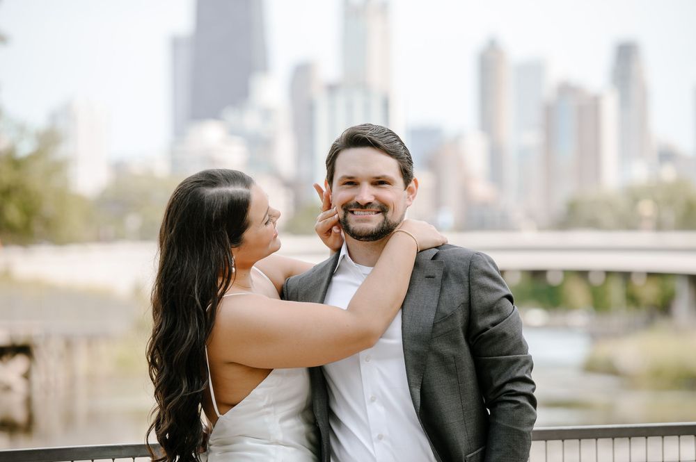 A joyful couple shares a romantic moment on a terrace with a city skyline in the background.