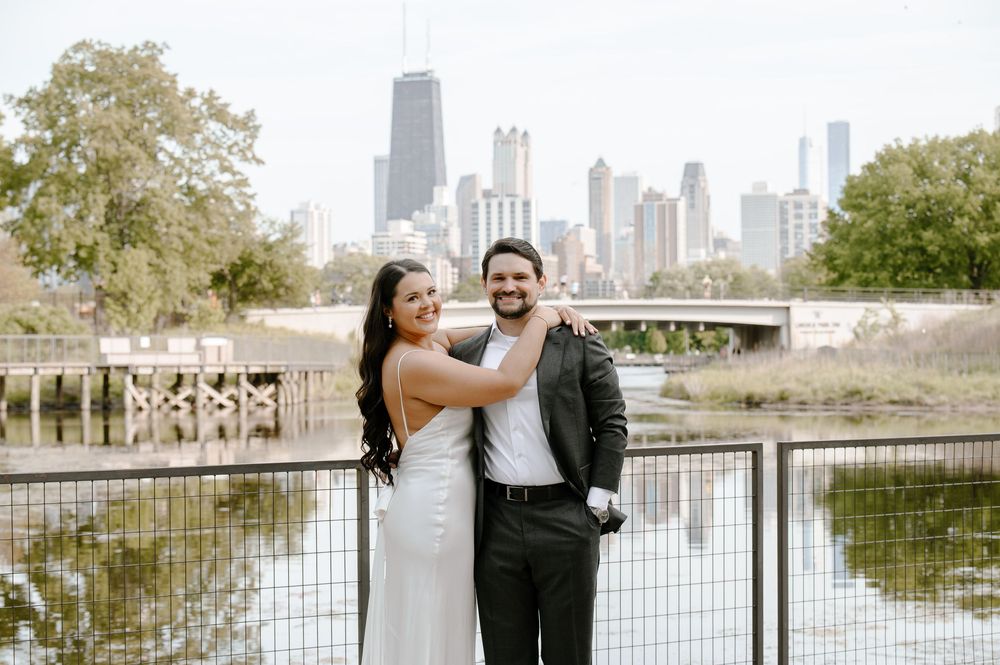 A couple embraces on a waterfront pier with the Chicago skyline visible in the background during an autumn afternoon.
