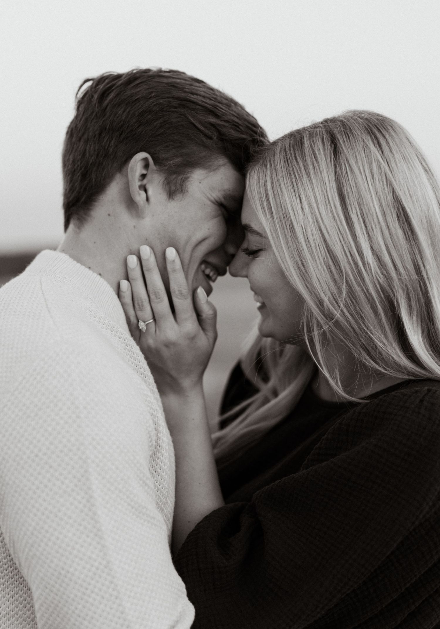 A romantic black and white intimate moment between a couple as they share a tender embrace outdoors.