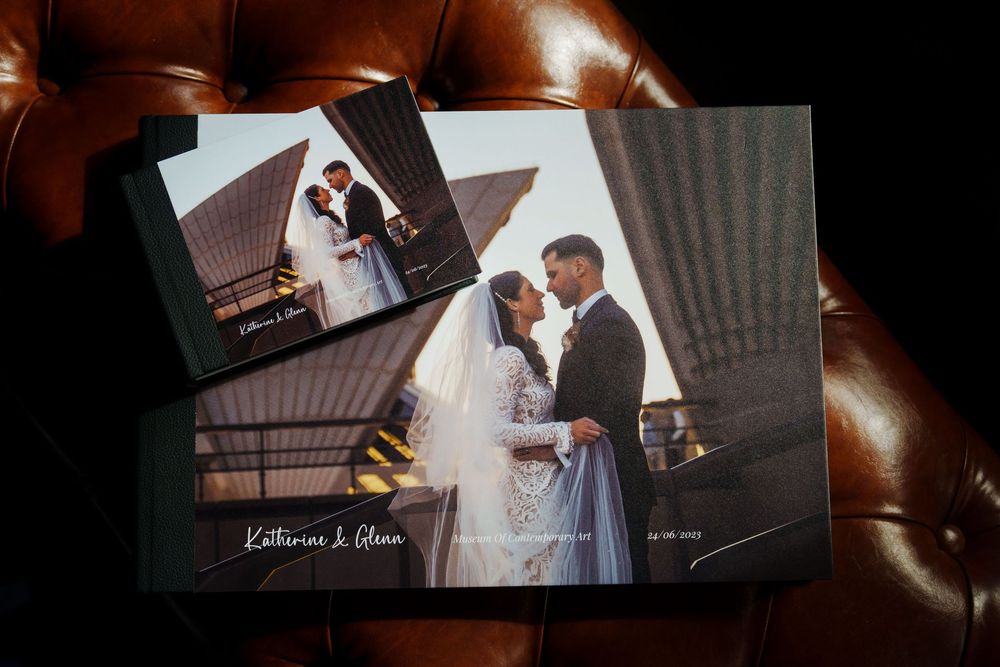 Wedding album with printed photographs showing bride and groom at their ceremony displayed on leather upholstery.
