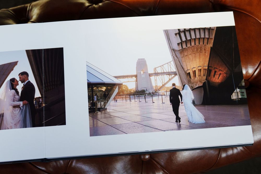 Wedding photo album showing bride and groom portraits next to Sydney Opera House against scenic harbor backdrop.