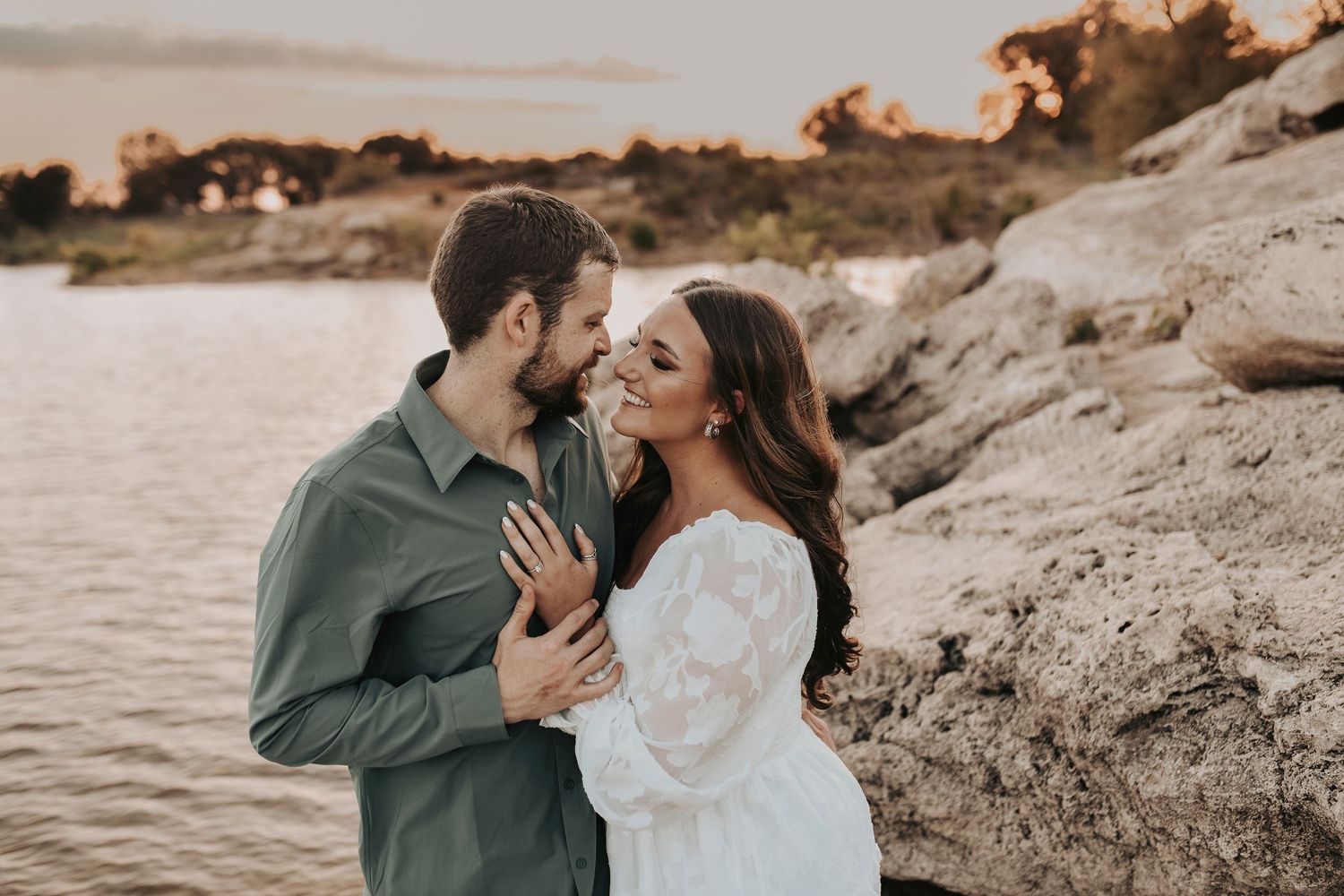 he looks sweetly at her while they pose for their engagement photos
