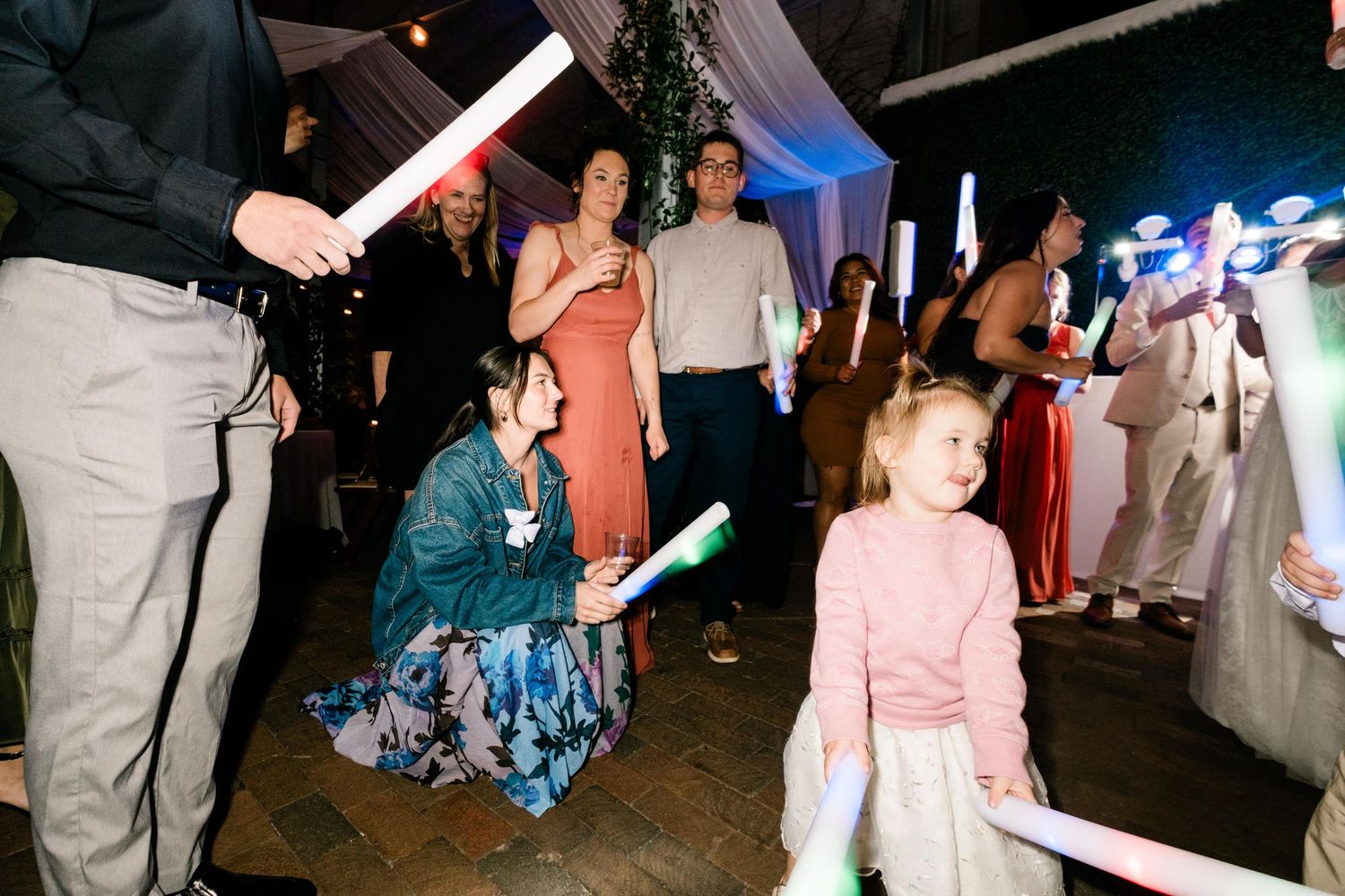 Guests at a nighttime wedding reception wave glowing lightsabers on the dance floor.