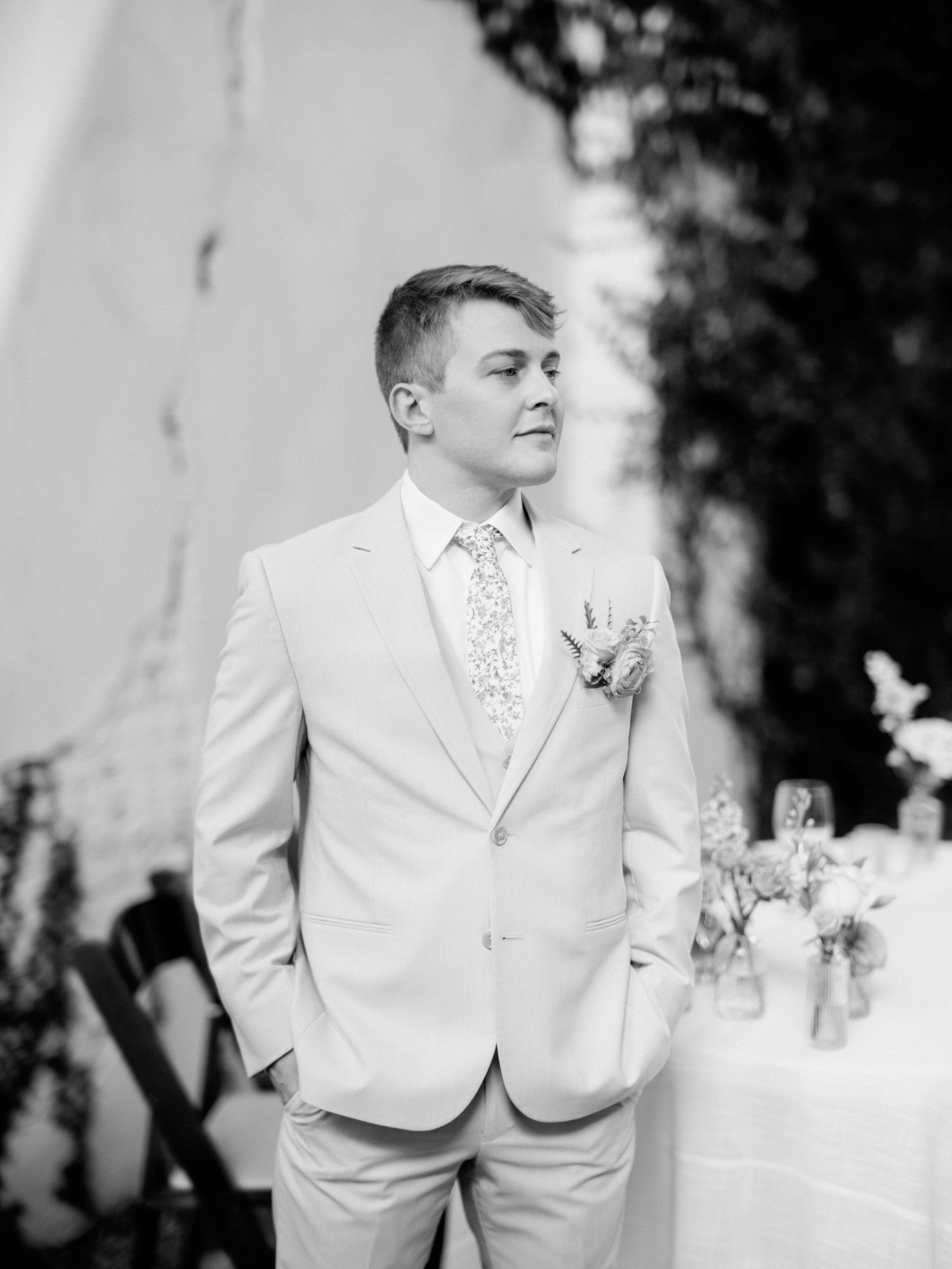 Groom in light colored suit poses during wedding ceremony.