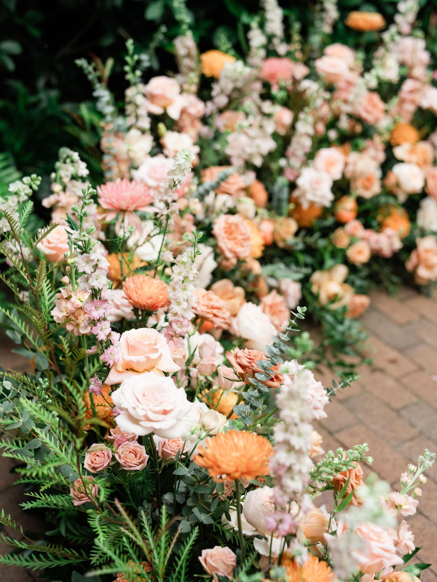 Beautiful peach and coral roses with delicate white flowers arranged along a garden pathway.