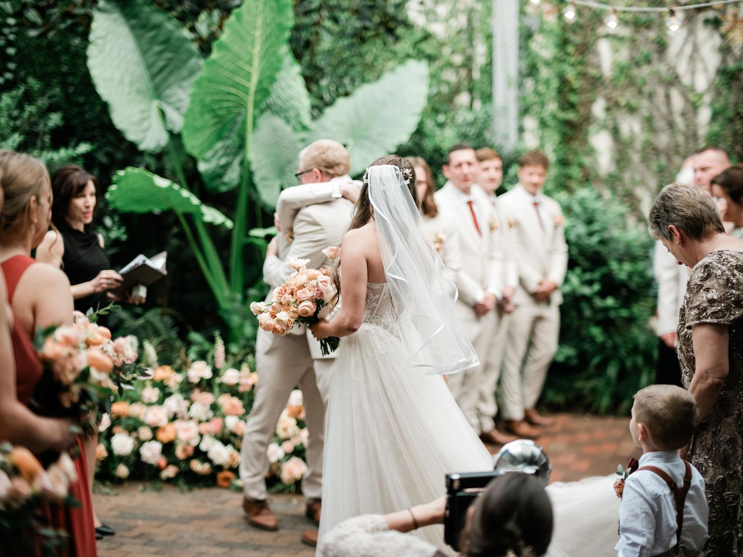 A wedding ceremony in a lush garden setting with guests watching the couple share their first kiss.