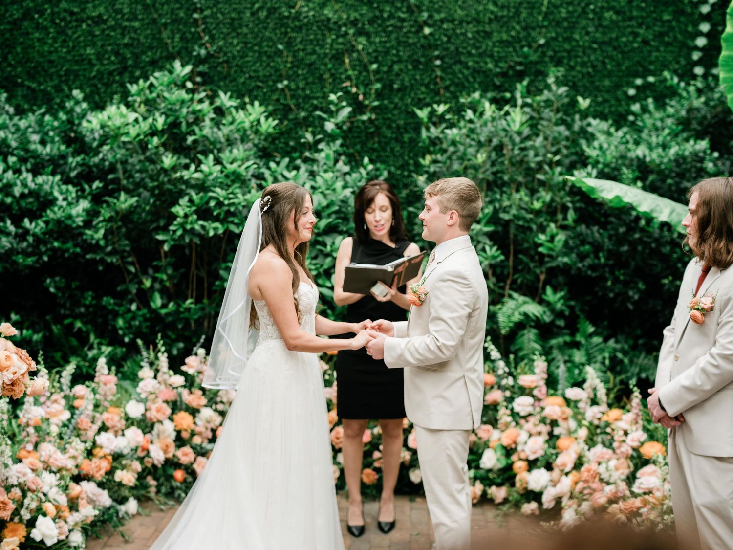 An outdoor wedding ceremony with florals and greenery creating a romantic garden setting.