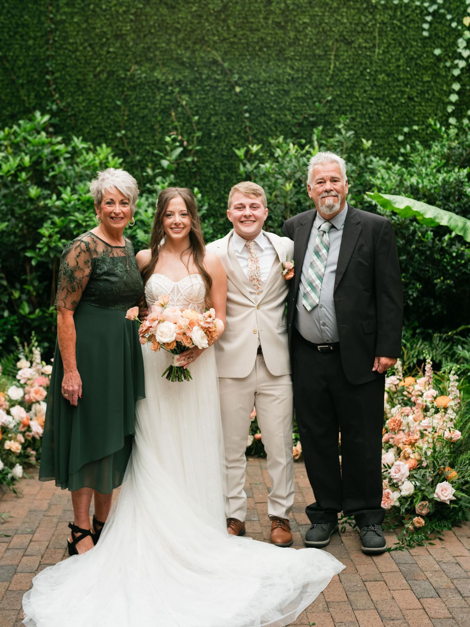 Wedding party poses together on a brick path surrounded by lush garden florals.
