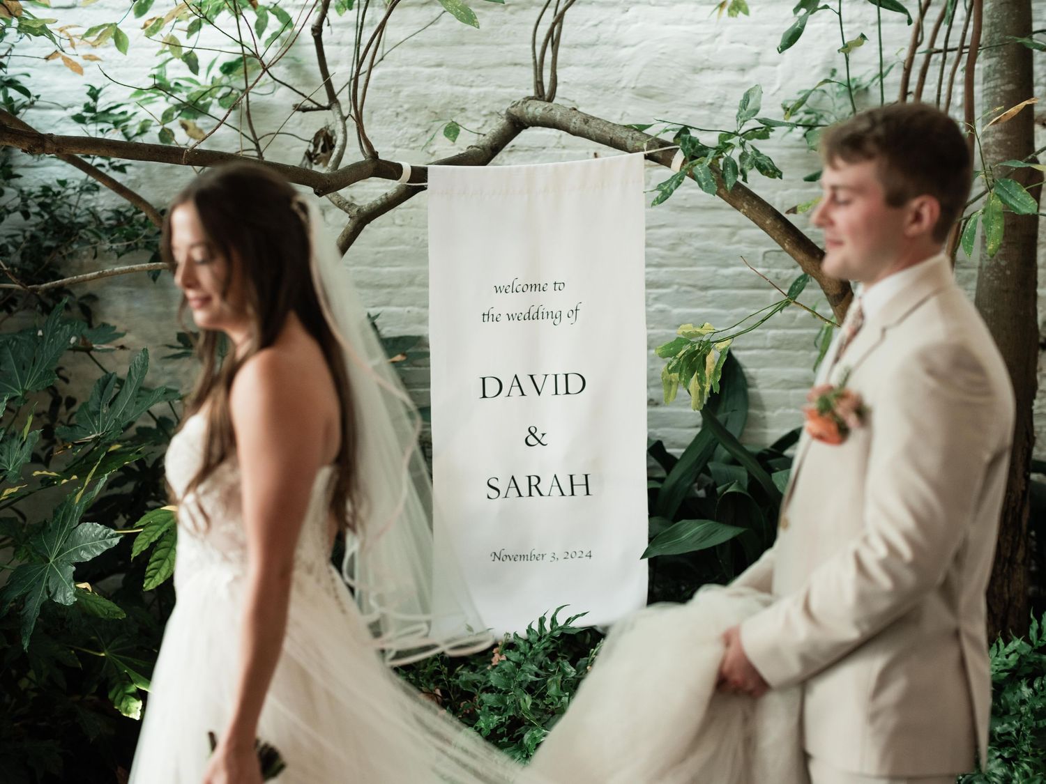 Wedding ceremony setup with white signage and greenery backdrop.