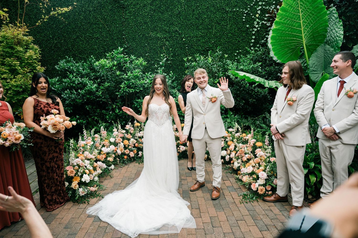 Garden wedding ceremony with floral arch and burgundy bridesmaids dresses.