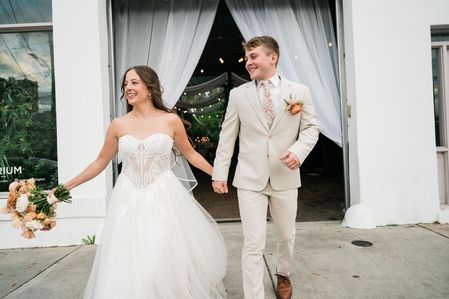 Newlyweds exiting their wedding venue with joyful expressions and classic attire.