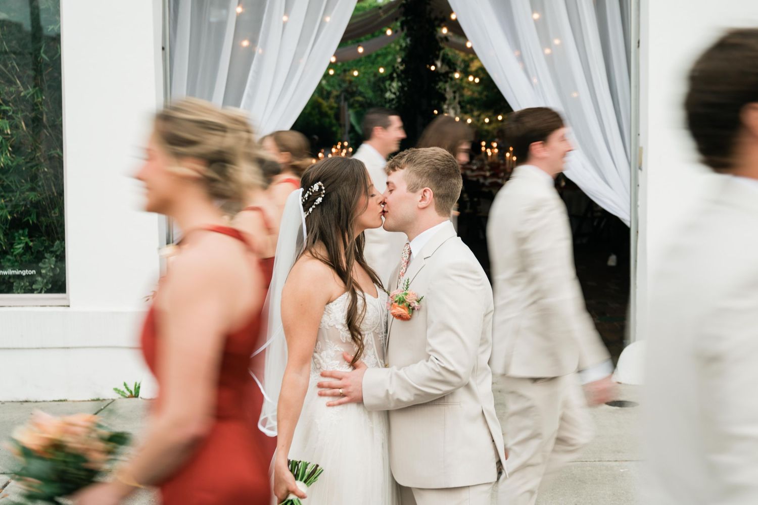 Motion-blurred wedding celebration moment with white drapes and twinkle lights as decor.