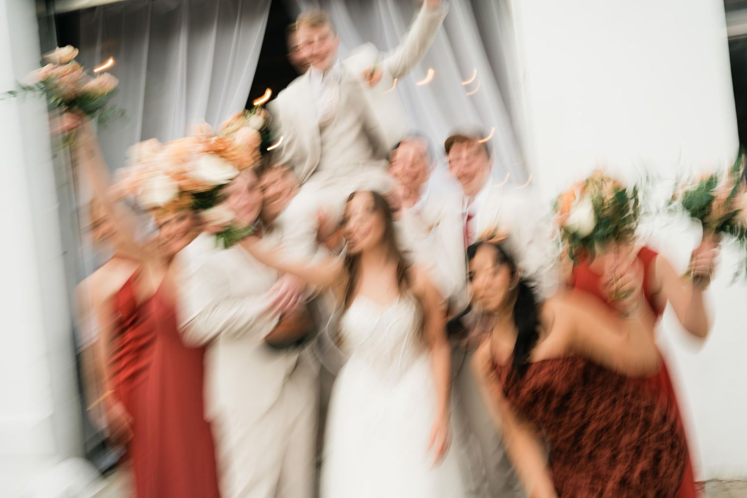 Motion-blurred artistic photo of wedding celebration with guests in festive attire.