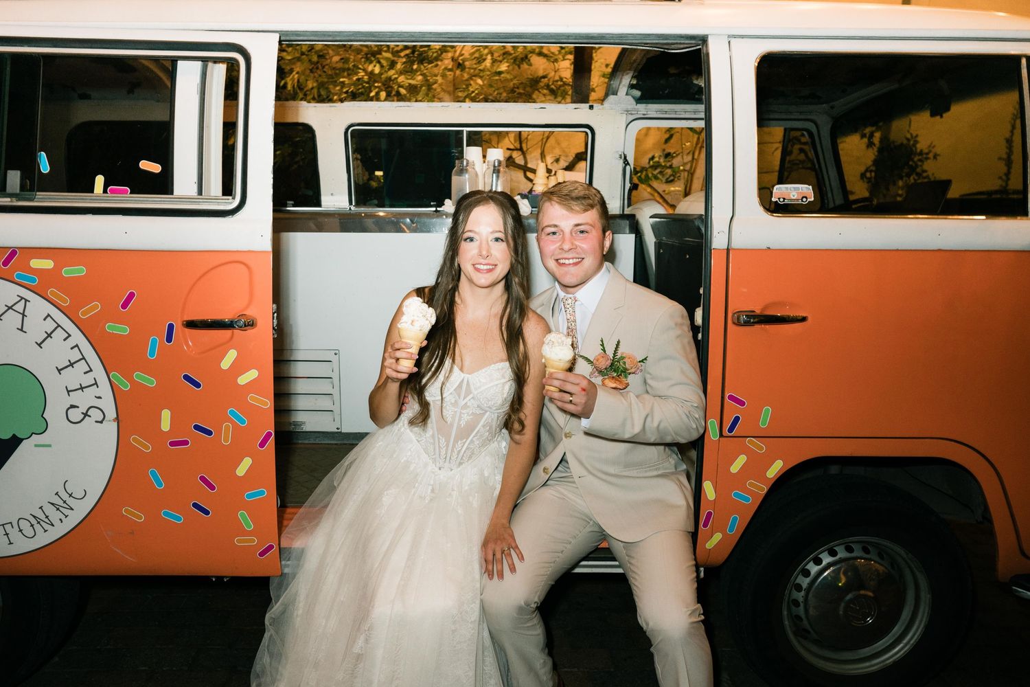 Orange and white vintage VW bus decorated for a wedding celebration serves as a fun photoshoot backdrop.